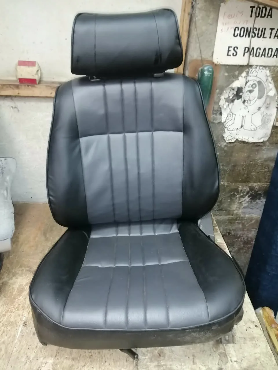 Asiento individual de vehículo forrado en vinil negro con panel central gris canalado
