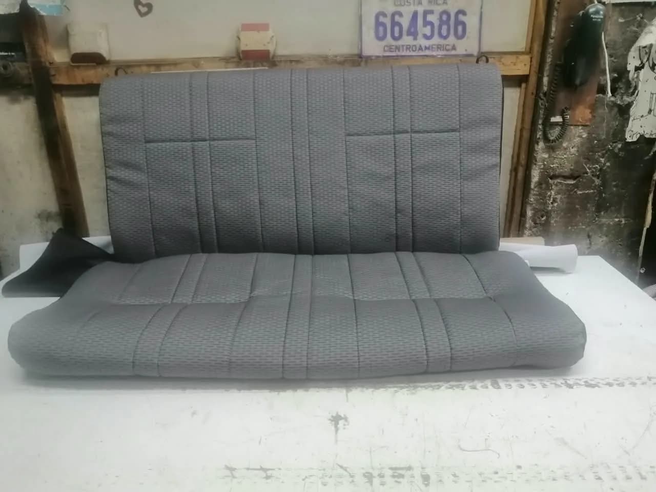 Banca de vehículo con respaldo abatible forrada en tela automotriz gris tejida