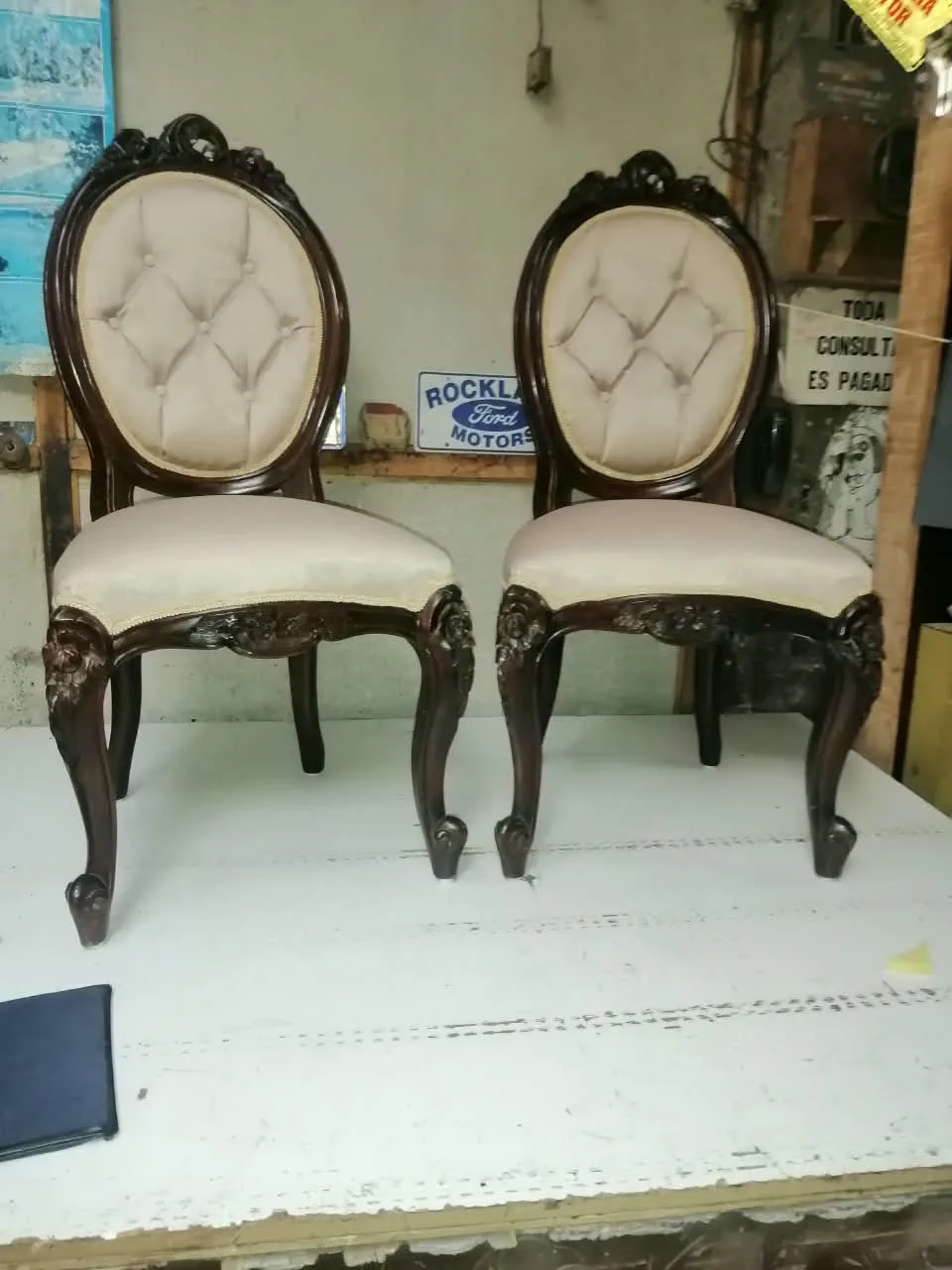 Dos sillas victorianas de respaldo medallón con talla floral y capitoné champaña