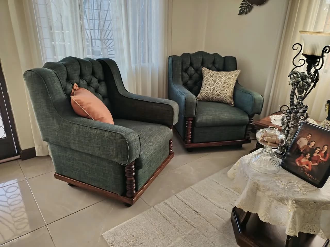 Par de sillones clásicos tapizados en lino verde con respaldo capitoné y columnas de madera torneada