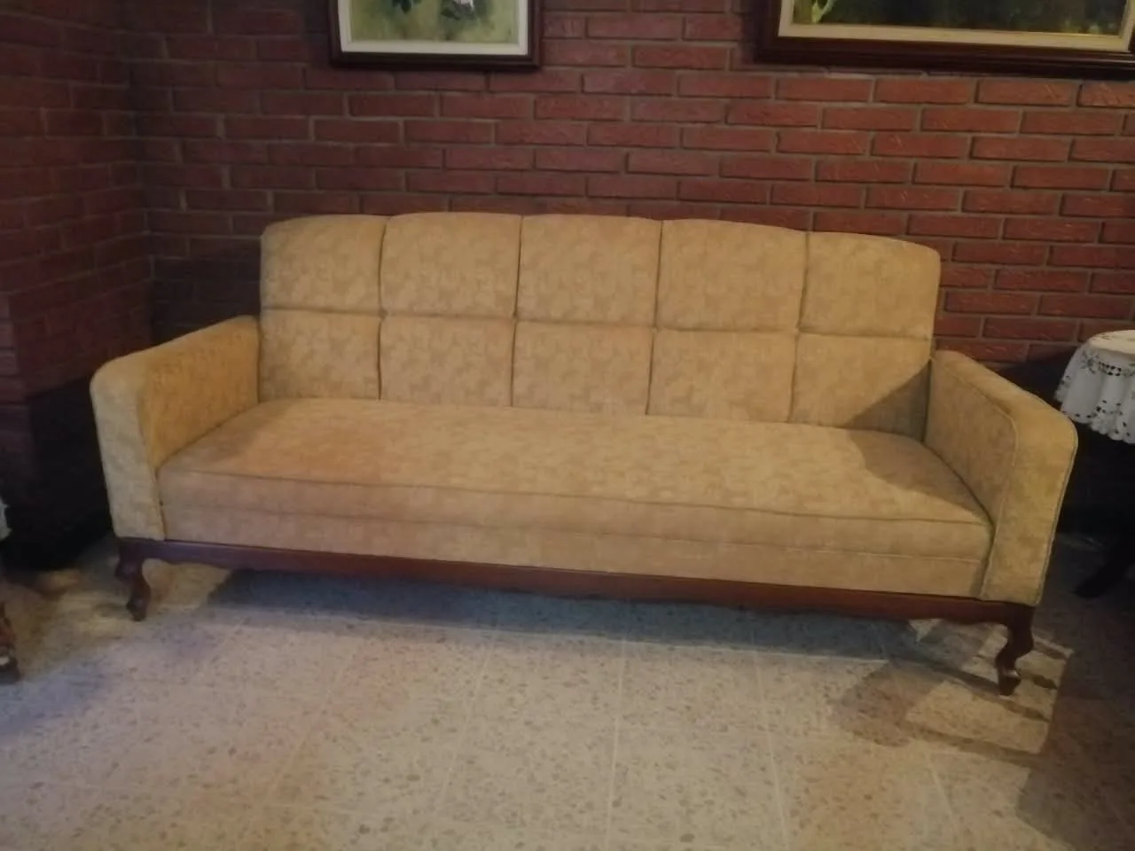 Sofá clásico tapizado en damasco beige con respaldo en paneles y patas cabriolé talladas