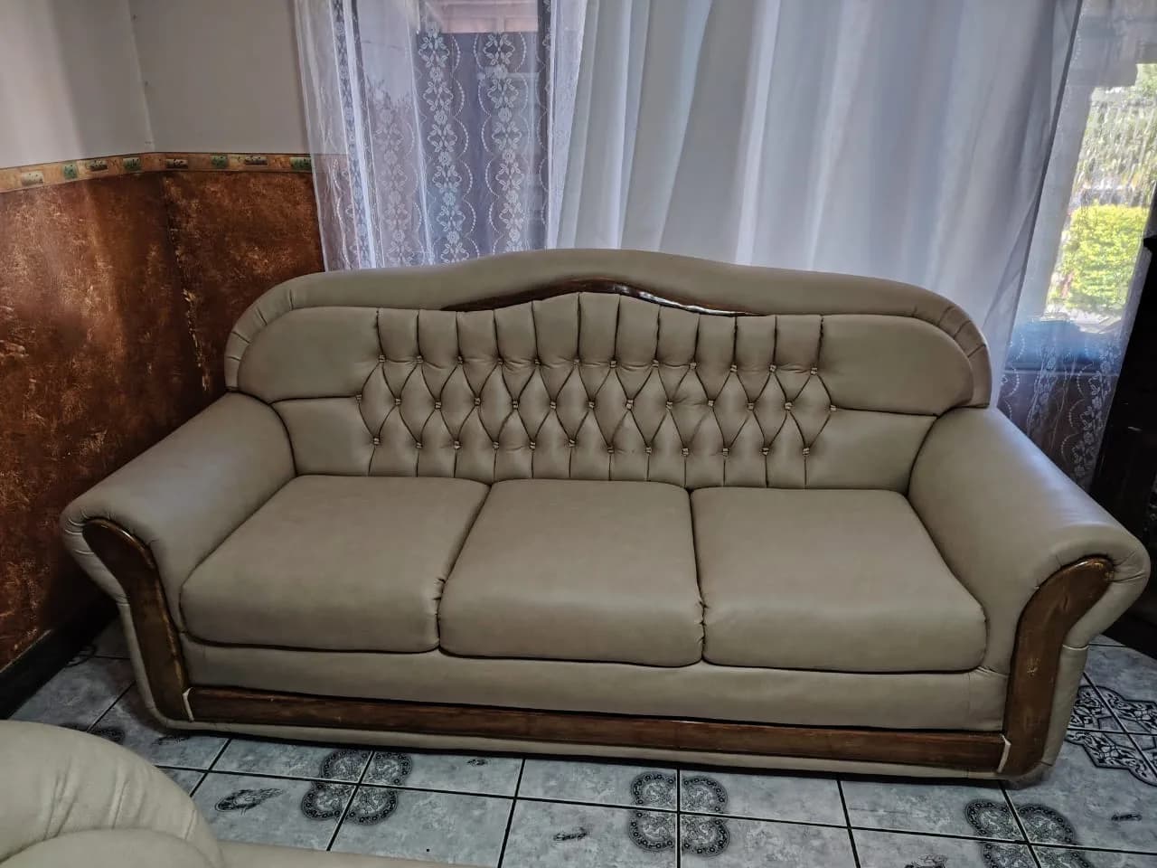 Sofá de tres puestos en cuero beige con respaldo capitoné en diamante y botón metálico