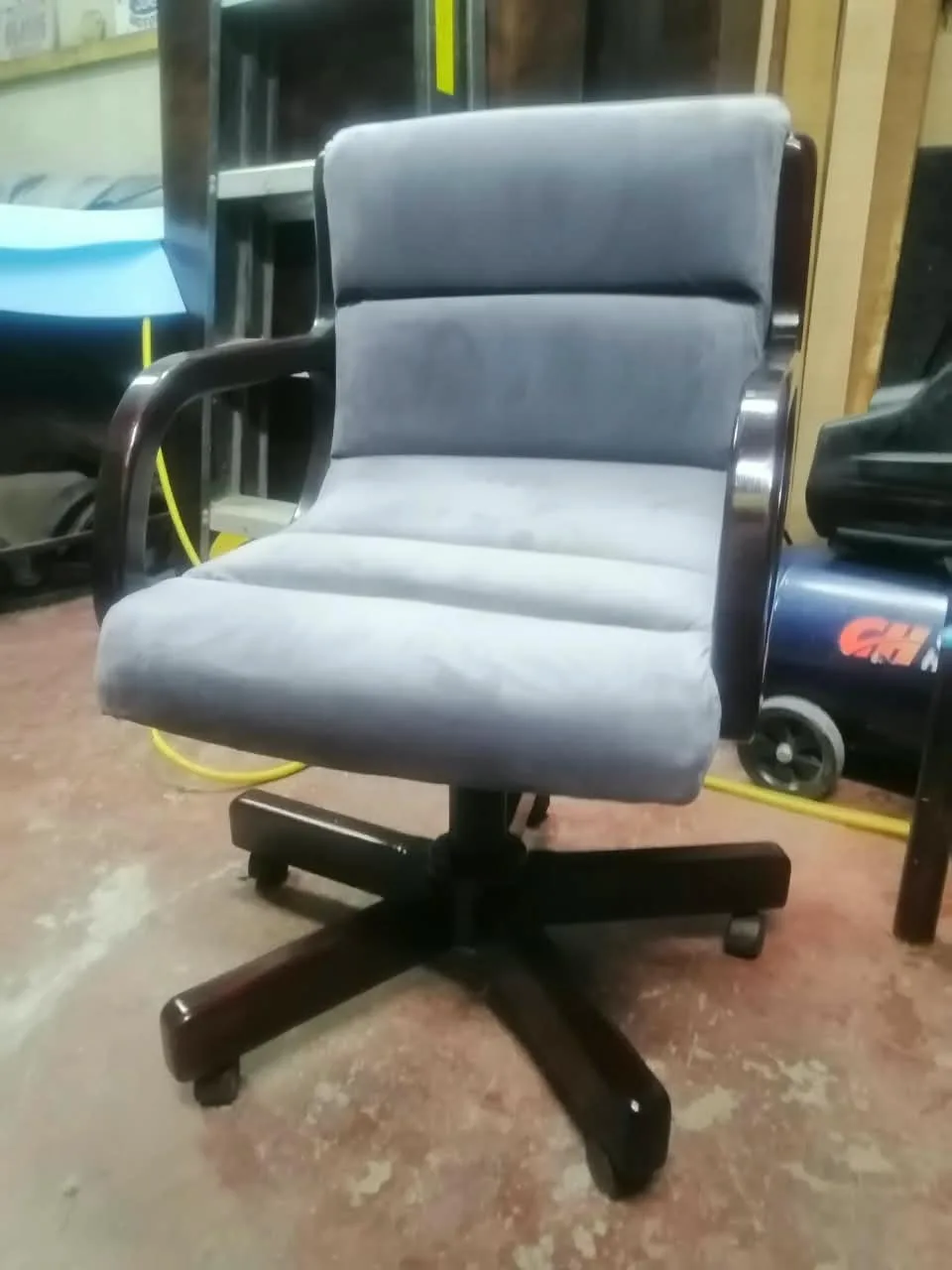 Silla ejecutiva giratoria tapizada en micro suede gris con brazos y base de madera barnizada