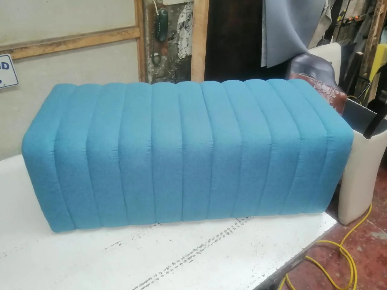 Banca rectangular tapizada en chenille turquesa con canales verticales continuos