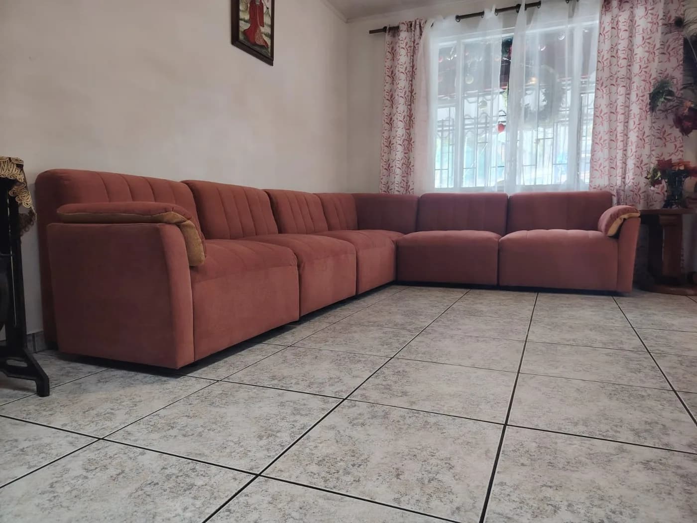 Seccional modular en L tapizado en micro suede terracota instalado en una sala