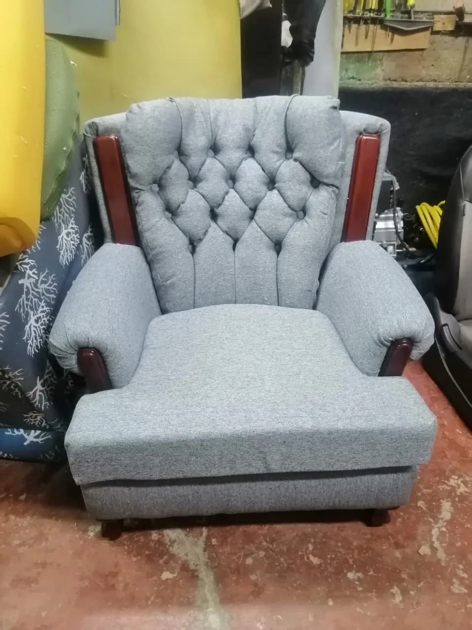 Sillón orejero tapizado en tela jaspeada gris con respaldo capitoné en diamante