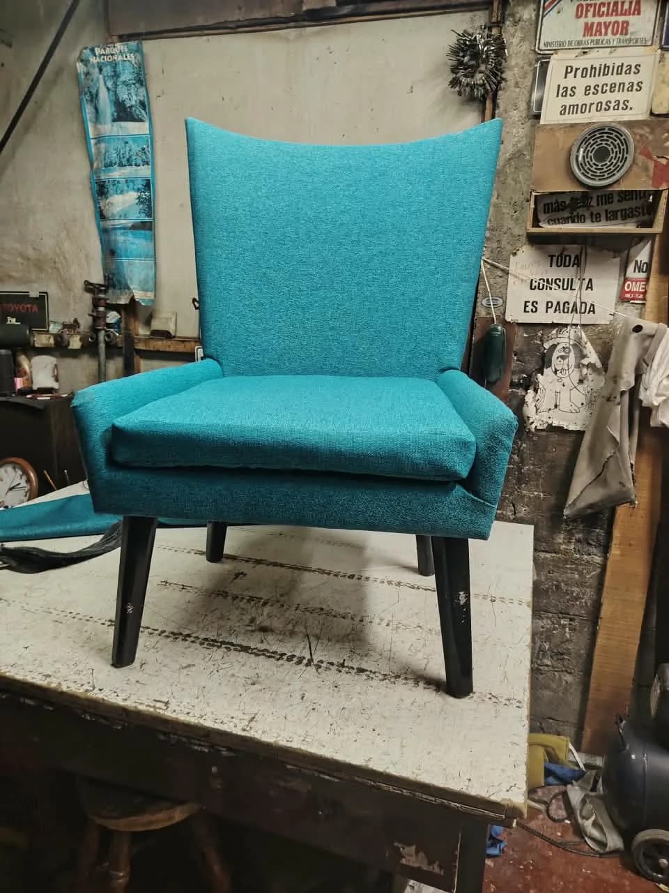 Sillón de respaldo alto tapizado en chenille turquesa con patas de madera negras